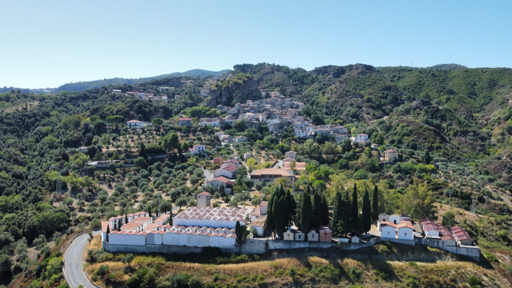 Luftaufnahme von Pietrapaola Paese, dem Friedhof und der Berglandschaft im Hinterland